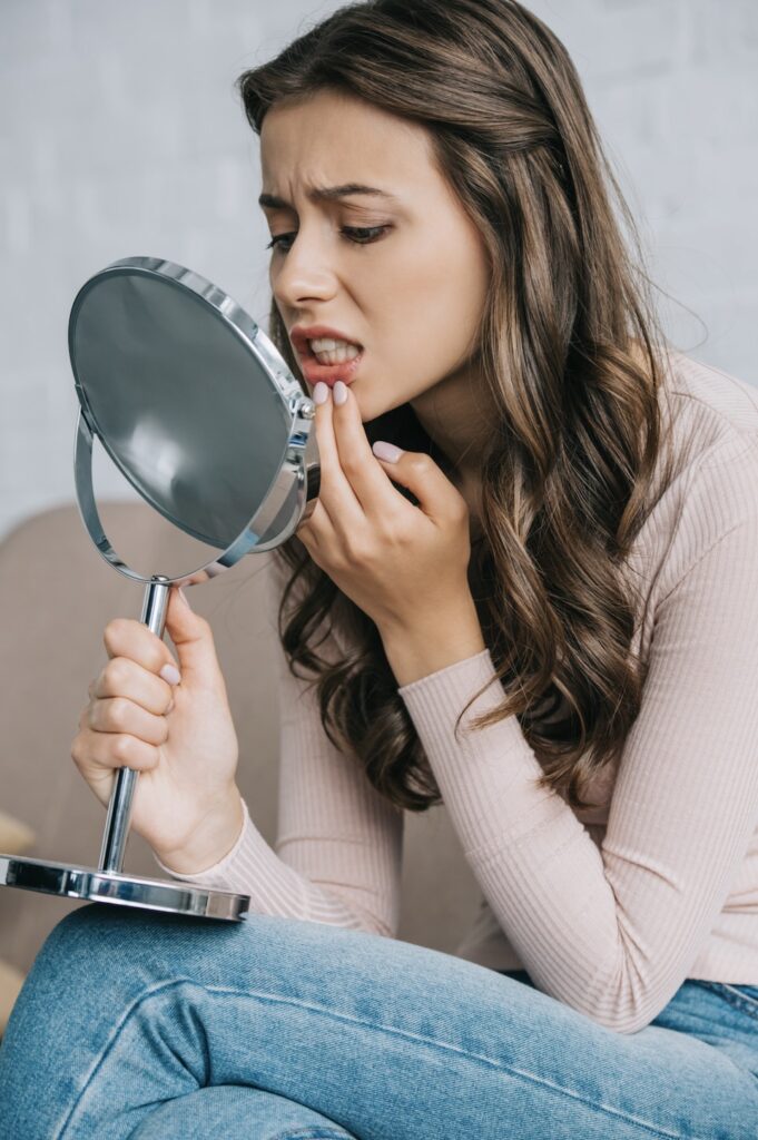 Woman with dental emergency looking in mirror